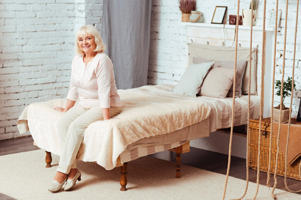 Grey-haired woman sat on bed