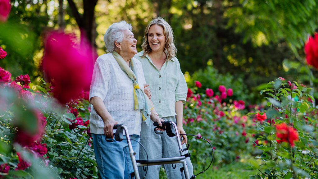 elderly woman and daughter walking with rollator in park