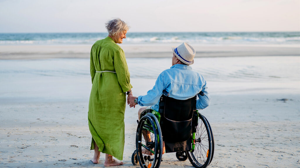 elderly couple holding hands at the beach